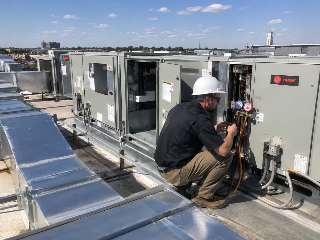 Airnet HVAC technician inspecting commercial rooftop HVAC package unit equipment